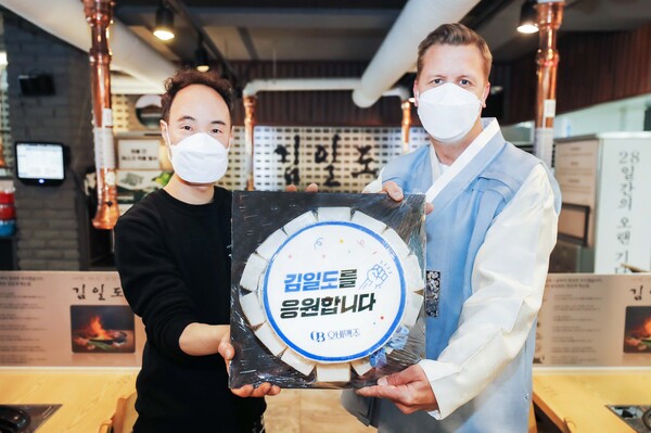 오비맥주 배하준 대표(오른쪽)가 강남구 삼성동 인근 음식점을 방문해 응원 메시지가 담긴 떡 케이크를 전달하고 있다./사진=오비맥주