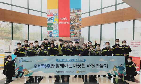 오비맥주 청주 생산공장 임직원들이 공장 인근 하천 정화 활동에 나서며 기념 사진을 찍고 있다./사진=오비맥주