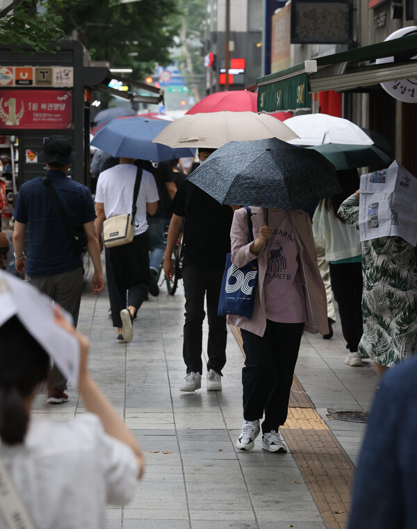  전국적으로 장마가 시작된 23일 오전 시민들이 서울 중구 을지로입구역 인근에서 우산을 쓰고 출근하고 있다./연합