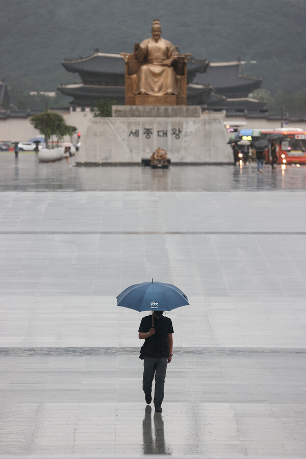 8일 오전 출근시간 한 시민이 서울 종로구 광화문광장에서 우산을 쓰고 걷고 있다. /연합