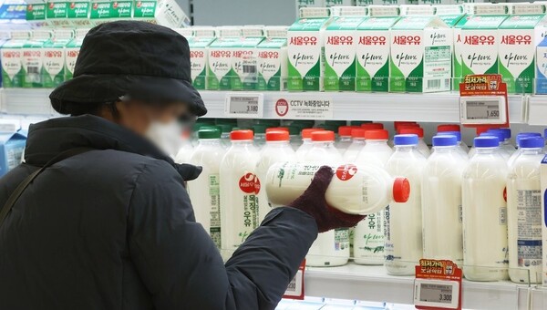 한 소비자가 마트에서 우유를 고르고 있다. /연합