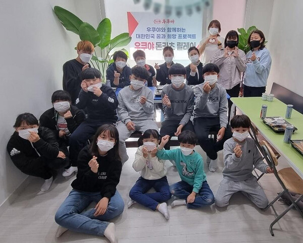 우쿠야가 제주 아동복지시설에 방문해 패밀리와 함께하는 돈카츠릴레이를 진행하고 사진을 촬영하고 있다. / 사진=BBQ