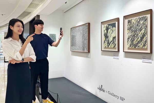 20일 갤러리아SP에서 모델들이 작품을 구경하며 사진을 찍고 있다. /갤러리아백화점