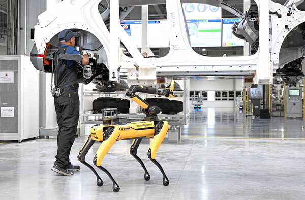 현대차그룹 싱가포르 글로벌 혁신센터에서 근로자가 아이오닉5를 조립하는 가운데 보스턴다이내믹스의 로봇 '스팟'이 작업 품질을 검사하고 있다./사진=현대자동차그룹
