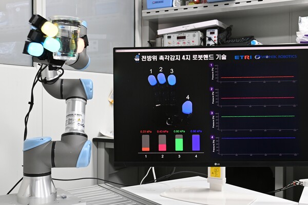 ETRI가 개발한 로봇 핸드가 물체를 잡자 압력 세기에 따라 로봇 손가락 색이 바뀌고 있는 모습./사진=ETRI