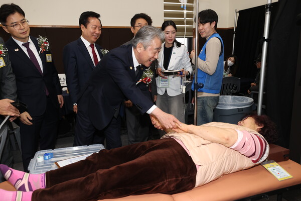 강호동 농협중앙회장이 2025년 2월 25일 안동시 일직중학교에서 환자용 침대에 누워있는 농업인의 손을 맞잡고 있다. / 사진=농협중앙회