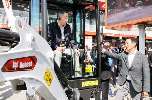 박정원 두산그룹 회장(왼쪽)이 바우마 2025에서 두산밥캣의 유럽시장 주력인 미니굴착기 신제품에 탑승해 스캇 박 두산밥캣 부회장(오른쪽)의 설명을 듣고 있다./2025.4.14.두산