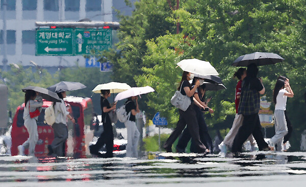 대구에 일주일째 폭염특보가 발효 중인 2025년 7월 3일 대구 달서구 계명대학교 인근 도로에 지열로 인한 아지랑이가 피어오르는 가운데 시민들이 양산을 쓰고 이동하고 있다./사진=연합뉴스