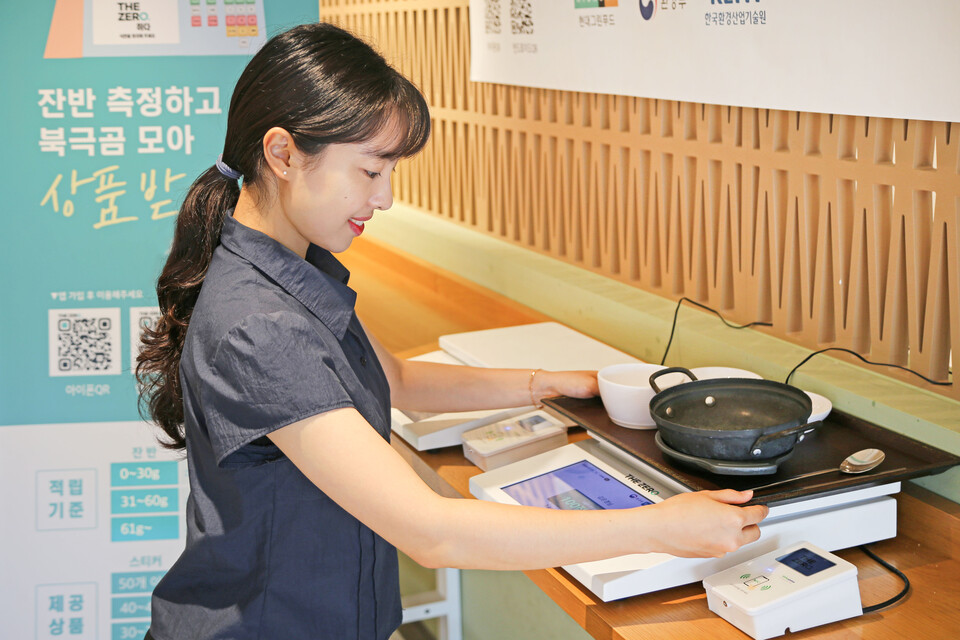 현대그린푸드가 운영 중인 단체급식 사업자에서 식사를 마친 고객사 임직원이 탄소중립포인트 제도 '잔반제로' 항목 참여를 위해 식판 무게를 재고 있다. 2025.7.17./사진=현대백화점그룹