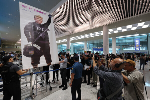 미국 이민당국에 의해 조지아주에 구금됐던 현대차-LG에너지솔루션 합작 배터리 공장 한국인 근로자들이 귀국한 12일 인천국제공항 제2여객터미널 입국장에서 도널드 트럼프 미국대통령 얼굴 배너를 든 시민단체가 시위하고 있다. 2025.9.12./연합
