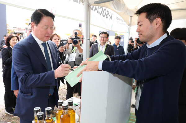 2025년 10월 30일 경주에서 열린 ‘APEC CEO 서밋’ 현장에 마련된 ‘K-사회적가치 기업관’에서 최태원 SK그룹 겸 대한상의 회장이 사회적 기업 제품에 싸인을 하고 있다./사진=대한상의