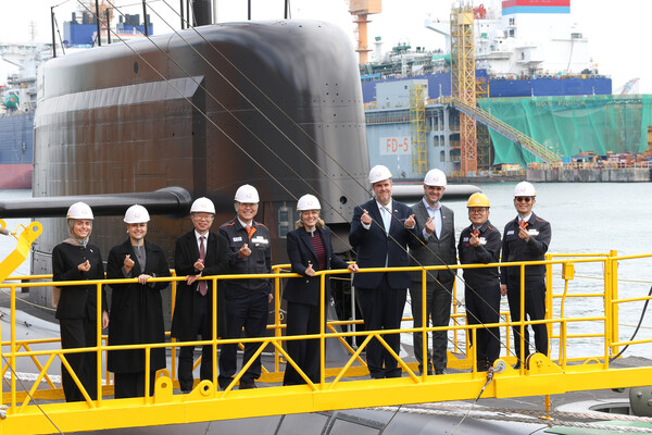 2025년 11월 24일 멜라니 졸리 캐나다 산업부 장관(가운데)이 김희철 한화오션 대표이사(왼쪽에서 네 번째), 강환석 방위사업청 차장(왼쪽에서 세 번째) 등과 함께 한화오션이 건조한 잠수함인 장영실함을 배경으로 단체사진을 찍고 있다./한화오션